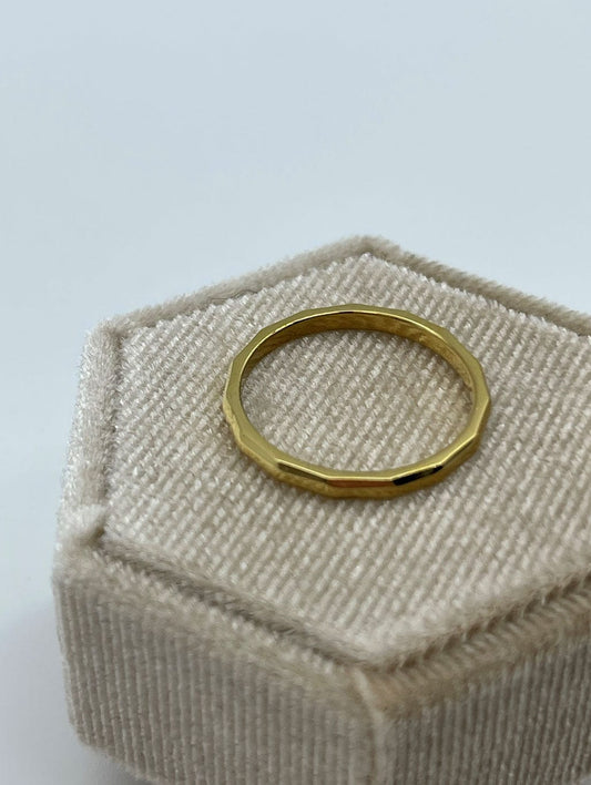 Enkel gullring som ligger på beige bakgrunn