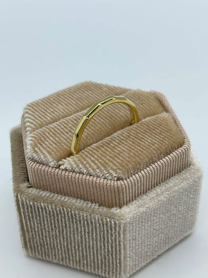 Gullbelagt kantete ring som står i en beige smykkeeske